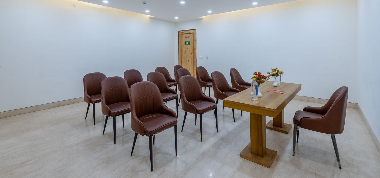  Front view of a conference room with a table placed between a chair and multiple chairs at DLS The Classio
